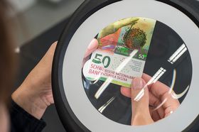 Contrôle à la loupe d’un billet de 50 francs fraîchement imprimé