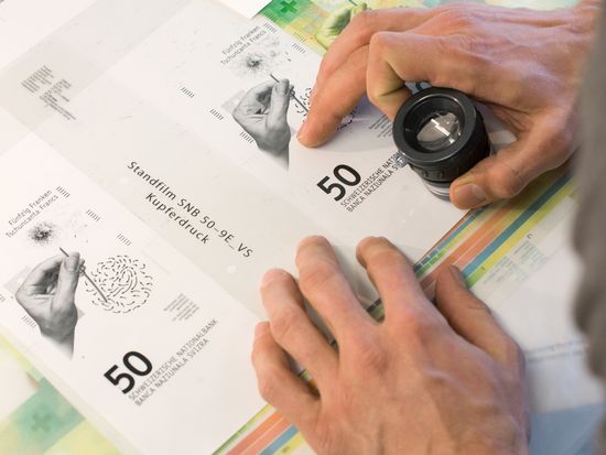 Graphic designer working on a detail of the note’s front